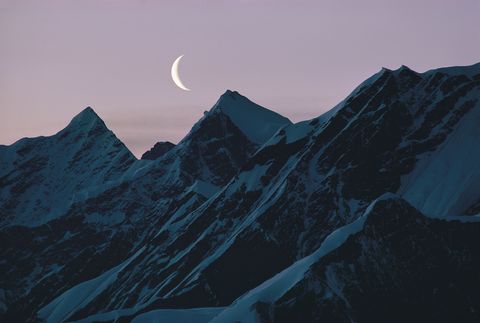 De bergen van Alaska worden beschenen door een afnemende maansikkel