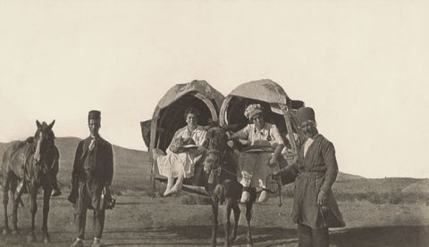 Mannen lopen langs twee Amerikaanse vrouwen die per kajeveh reizen draagstoelen die iets weghebben van manden die werden gebruikt in het gebied dat toen bekend stond als Perzi