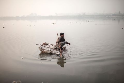 In Delhi vist een dakloze jongen naar muntjes door met een magneetje aan een touw de bodem van de Yamuna de belangrijkste zijrivier van de Ganges af te zoeken