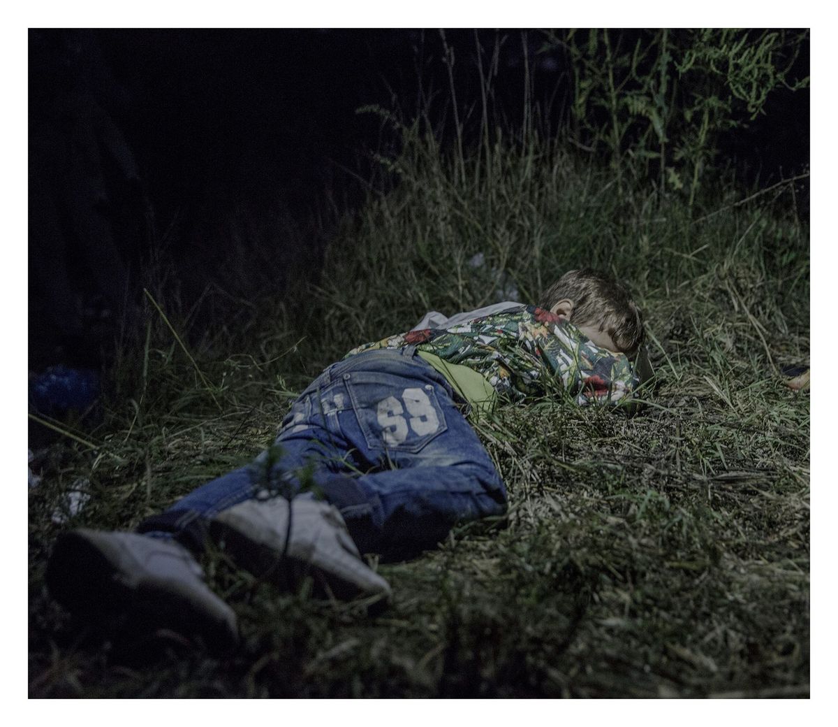 Terwijl volwassenen plannen maken om aan de autoriteiten in Hongarije te ontkomen slaapt Ahmed 6 in het gras Nadat zijn vader in het noorden van Syri werd gedood heeft Ahmed lopend met zijn familie afstanden afgelegd Hij draagt onderweg zijn eigen tas