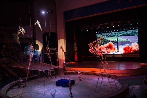 Een video van een raketlancering wordt op een groot scherm geprojecteerd terwijl acrobaten als raketten door de lucht vliegen tijdens een circusact in Pyongyang