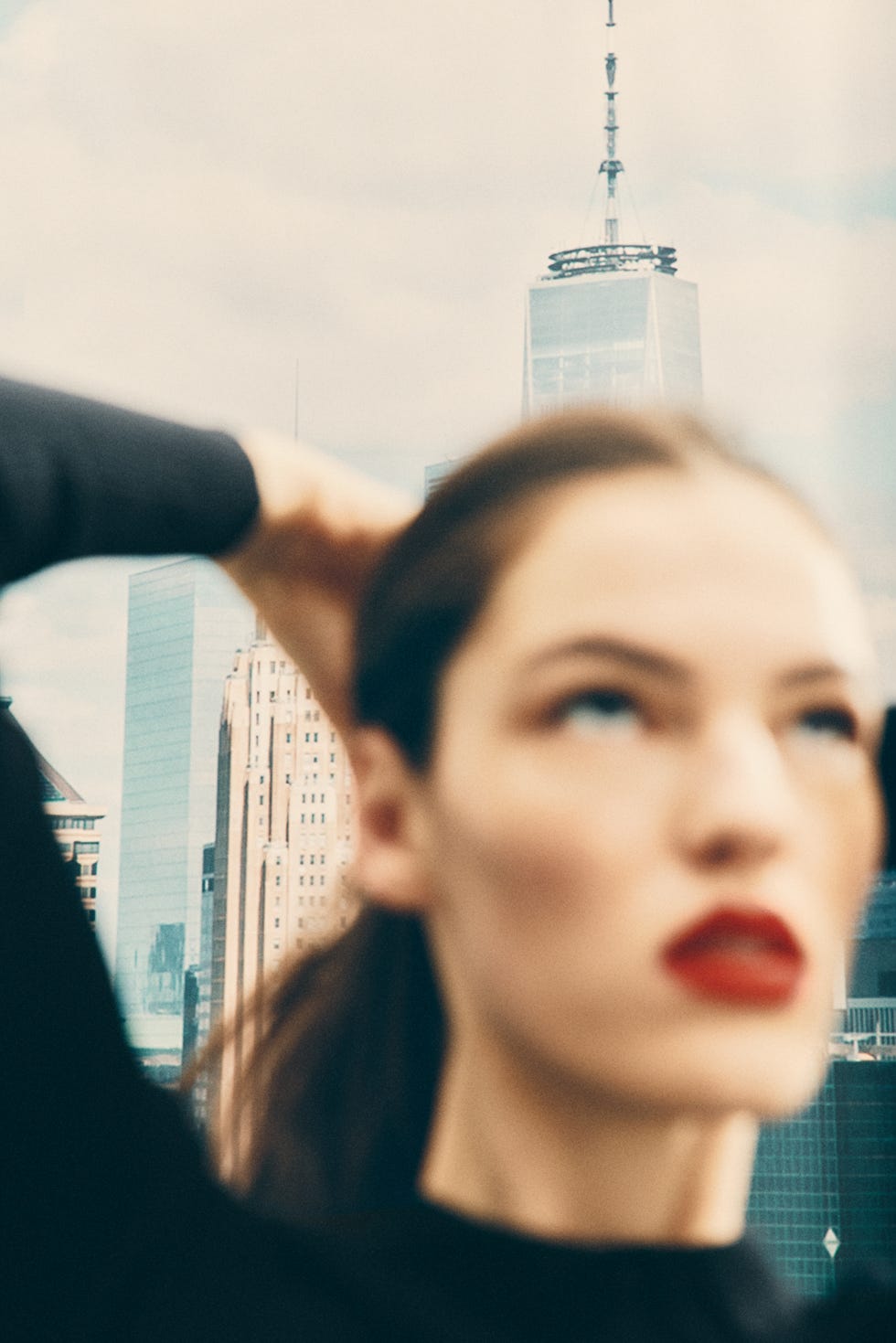 person with their hair tied back in front of a city skyline