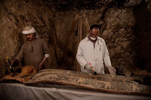 Een sarcofaag en een dodenmasker uit de pas ontdekte tombe Kampp 150 worden door Egyptische medewerkers voorzichtig schoongemaakt