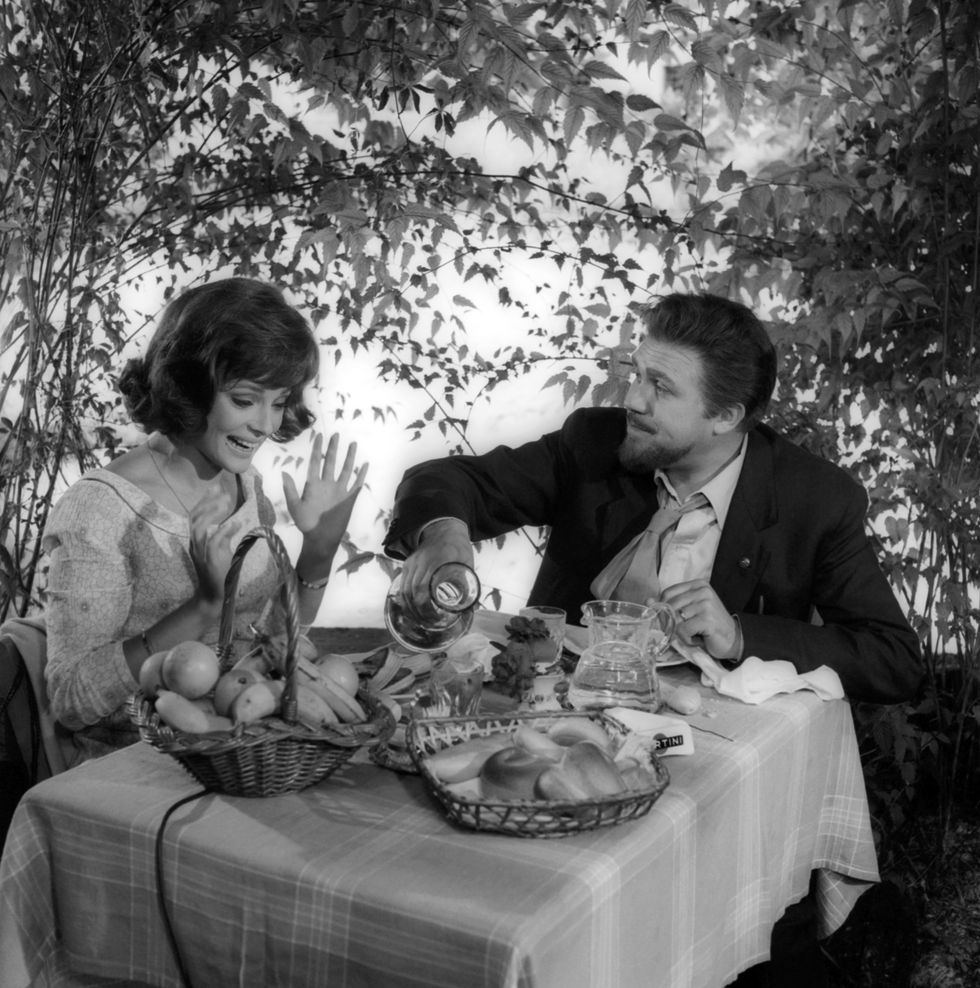 a man and woman sitting at a table with food