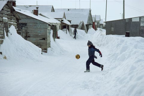 In een ingesneeuwd straatje in Barrow Alaska schopt een jongen tegen een voetbal