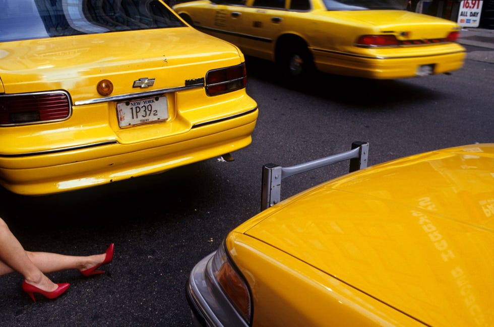 Vrouwenbenen met rode schoenen met hoge hakken en taxis op Times Square