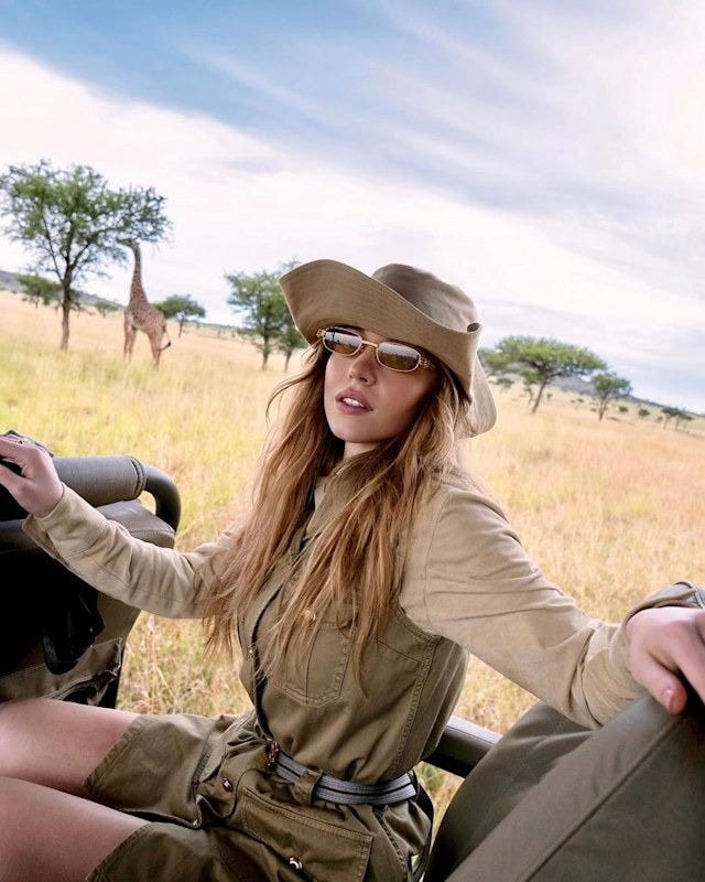 persona su un veicolo da safari con una giraffa sullo sfondo
