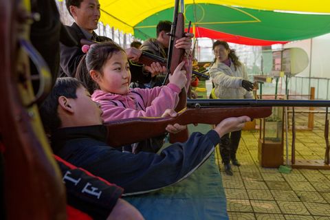 Kermissen en carnaval is populair in heel NoordKorea Op deze foto schieten kinderen met speelgoedpistolen bij een kermisspel