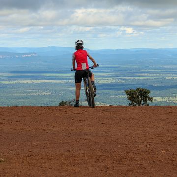 a person riding a bike on a dirt hill with a body of water in the background