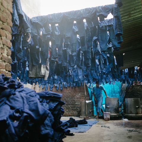 In Silampur een van de meest vervuilde en dichtstbevolkte districten van Delhi werkt een man in een fabriek waar jeans blauw worden geverfd