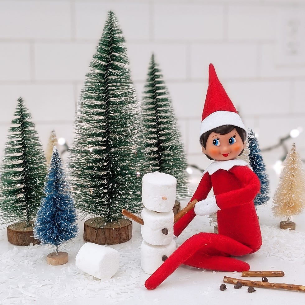 an elf builds a snowman out of marshmallows with pretzelstick arms