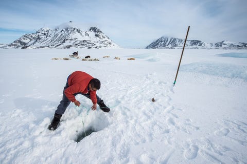 Een Inuitman is aan het vissen in OostGroenland Inuit leven in de winter van de jacht en de visvangst Dit wordt steeds moeilijker door klimaatverandering en krimpende populaties van soorten