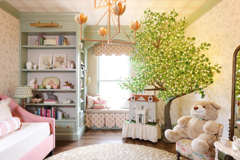 girl's playroom with light green bookshelves, a tree with lights, and a dollhouse.