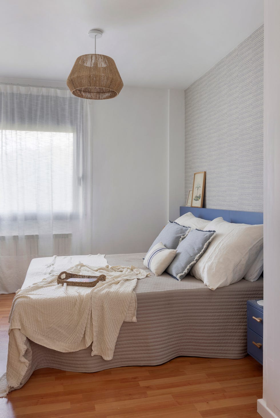 dormitorio con cabecero y mesita azul y lámpara de techo de yute