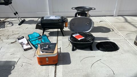 a picture of the everdure cube, pk go, biolite and solostove grills arranged on a sunny driveway as part of good housekeeping's portable grill test