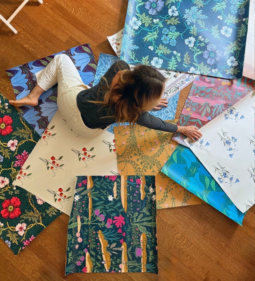 Person arranging various patterned papers on a wooden floor.