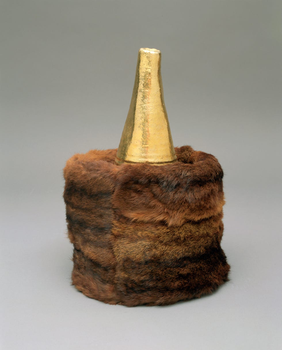 Container with a fur exterior and a golden cone-shaped lid.