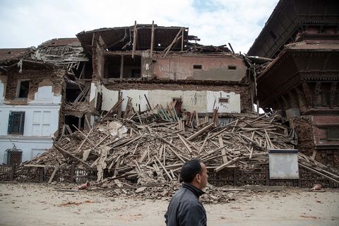 Een man passeert een ingestorte tempel bij het Durbarplein in Kathmandu dat wordt omringd door talloze historische paleizen