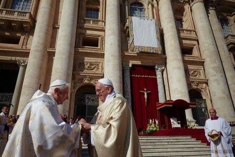 Franciscus begroet zijn voorganger emeritus paus Benedictus bij een heilige mis aan het eind van de bisschoppelijke synode over het gezin en de viering van de heiligverklaring van paus Johannes Paulus VI