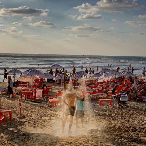 TEL AVIV ISRAL  Badgasten spoelen zich af onder een trekdouche op het strand van Tel Aviv Isral Populaire strandactiviteiten in Isral zijn windsurfen volleybal surfen zeilen en paddleboarding