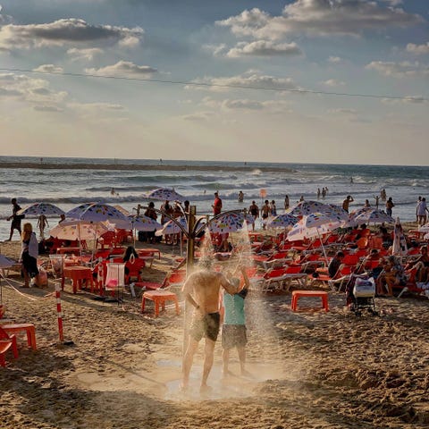 TEL AVIV, ISRAËL TEL AVIV ISRAL Badgasten spoelen zich af onder een trekdouche op het strand van Tel Aviv Isral Populaire strandactiviteiten in Isral zijn windsurfen volleybal surfen zeilen en paddleboarding