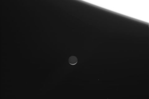 Op deze foto van Cassini die op 14 september werd gepubliceerd is Enceladus als een smalle sikkel onder de heldere massa van Saturnus te zien