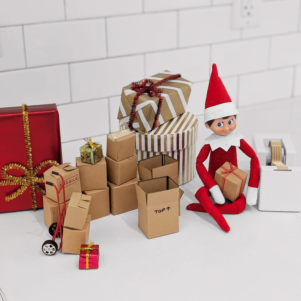 an elf sits amid a pile of boxes, and a couple of wrapped one