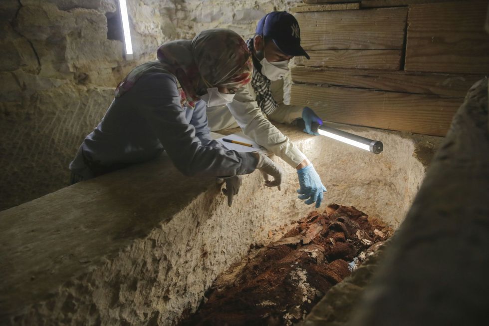 Archeologen Maysa Rabeeh links en Mohammed Refaat rechts onderzoeken de vergane houten doodskist van een priester genaamd Ayawet die is begraven met gekruiste armen  een goddelijke positie die normaal alleen was toegestaan voor faraos