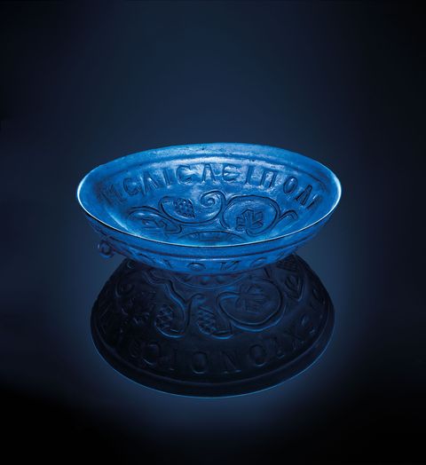 Deze 1700 jaar oude drinkschaal van transparant blauw glas heeft een doorsnede van 21 centimeter en werd gevonden naast een vrouw die in het centrum van een Romeinse begraafplaats was bijgezet De Griekse inscriptie luidt Drink om vele jaren eeuwig te leven