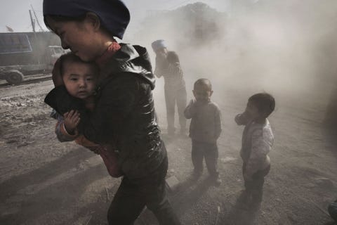 Inwoners van Wuhai in BinnenMongoli raken bedekt door het stof afkomstig van een passerende vrachtwagen met kolen en kalk