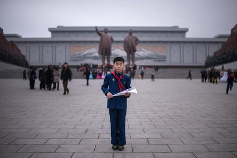 De 11jarige Kim Su Min poseert voor de fotograaf voordat hij zal deelnemen aan een feestelijke traditie het leggen van bloemen bij de standbeelden van de overleden NoordKoreaanse leiders Kim Il Sung linksboven en Kim Jong Il rechtsboven op de heuvel Mansudae in Pyongyang