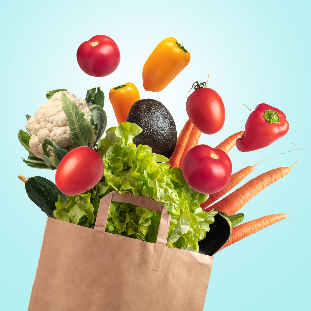 grocery bag of fresh vegetables on blue summer sky background