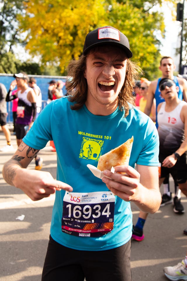 a man holding and pointing to a sandwich