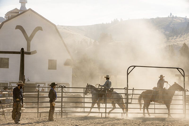 Cowboys in dusty ranch environments with a barn in the background