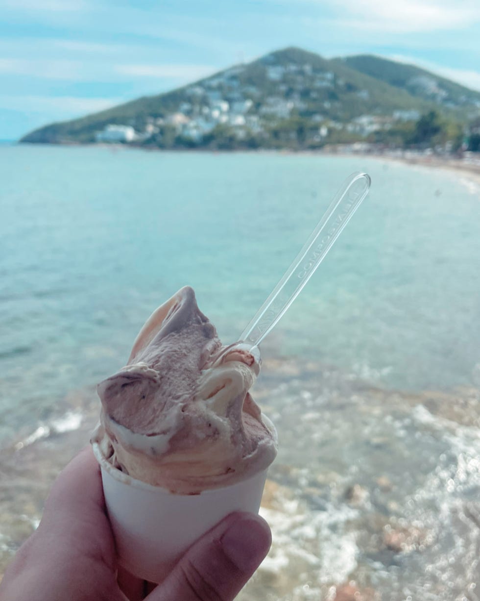 gelato a hand holding a cup of ice cream with a spoon