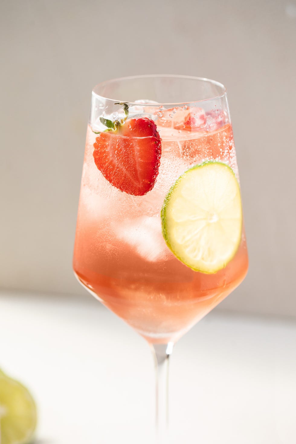 pink cocktails lillet rose spritz with strawberry and lime slice in a wine glass