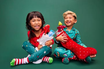 two children sitting on a green background holding christmas stockings