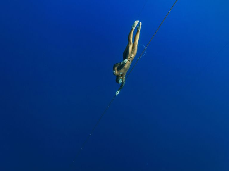 a person diving in blue water, wearing a yellow wet suitdiving gear