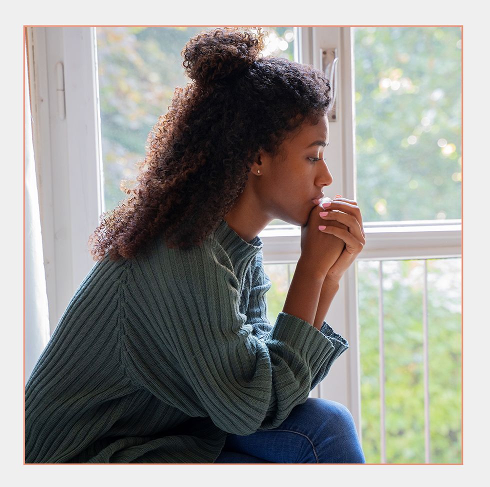 woman thinking while sitting by window alone