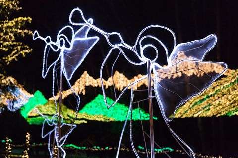 two angels blowing horns outlined in lights with lights shaped like mountains in the background