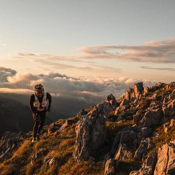 hiker navigating rocky terrain at sunset with clouds in the distance hiker navigating rocky terrain at sunset with clouds in the distance