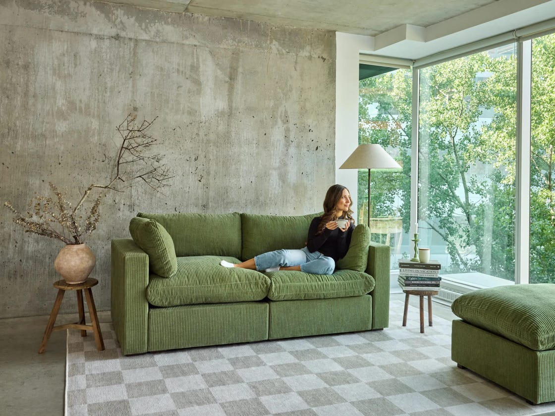 a cozy living room with a green sofa and a view of nature