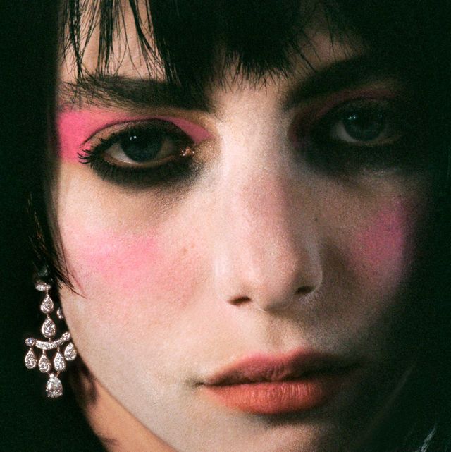 close up image of devon ross with dramatic pink eye makeup and chandelier earrings