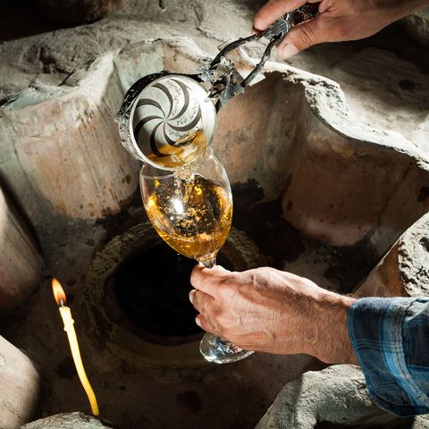 Winemaking has deep roots in the nation of Georgia where a vintner pours a traditional white wine from a cup inscribed with the names of his forebears