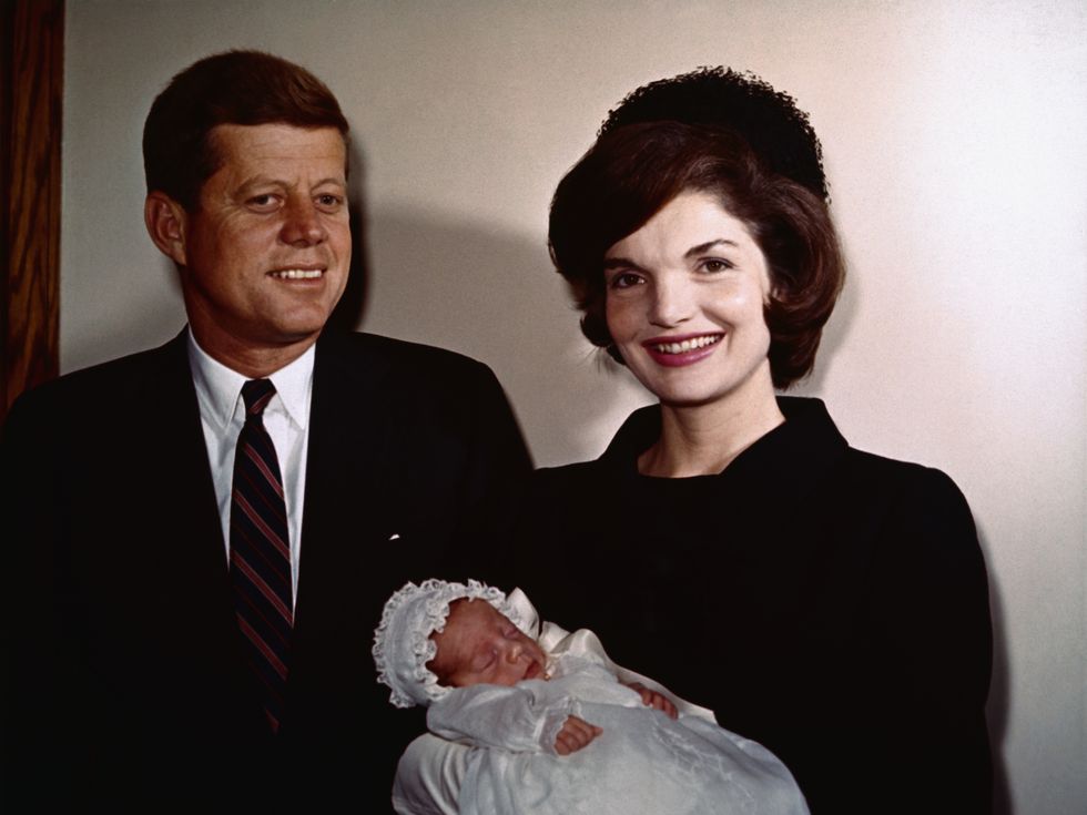 President John F. Kennedy with wife Jackie who is holding their son, John Jr., during his christening.