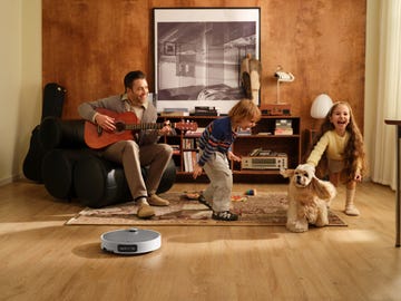 family interacting in a living room with a pet while a robotic vacuum is cleaning the floor