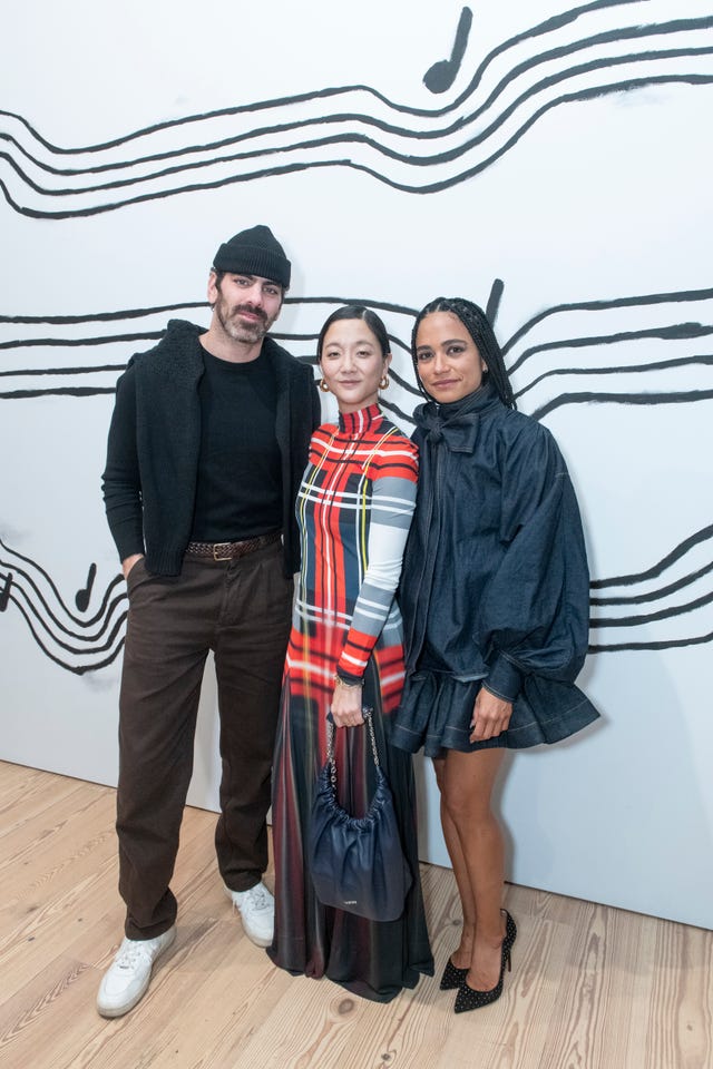 three individuals posing in front of a musical notes design