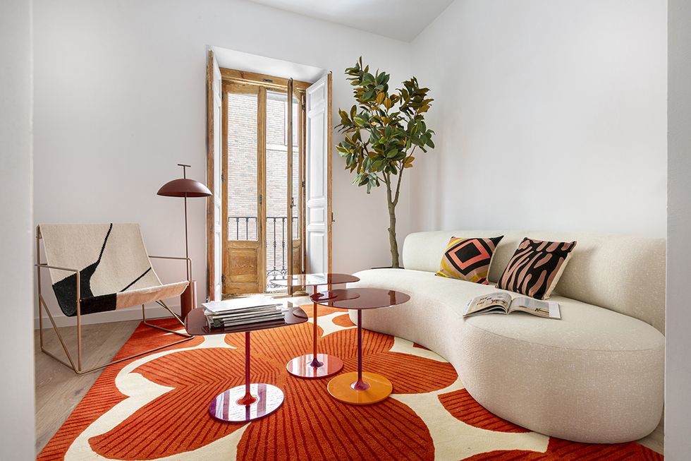 una salon con sofa curvo en blanco y alfombra naranja