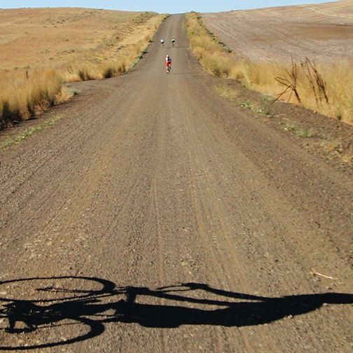man on bike riding on long gravel road