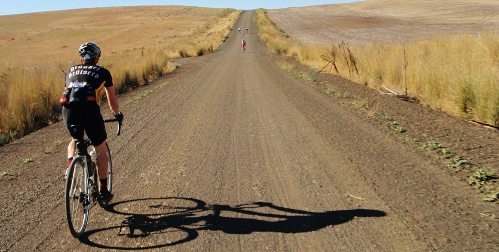 man on bike riding on long gravel road